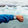 Homme devant un glacier qui montre sa montre avec un bracelet milanais argenté pour le petit je ne sais quoi
